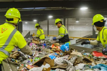 66901ab5a5104482f7806d5a_Banner_Large industrial recycling facility with workers and machinery